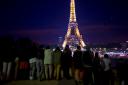 Tourists look at the illuminated Eiffel Tower in Paris (Thibault Camus/AP, File)