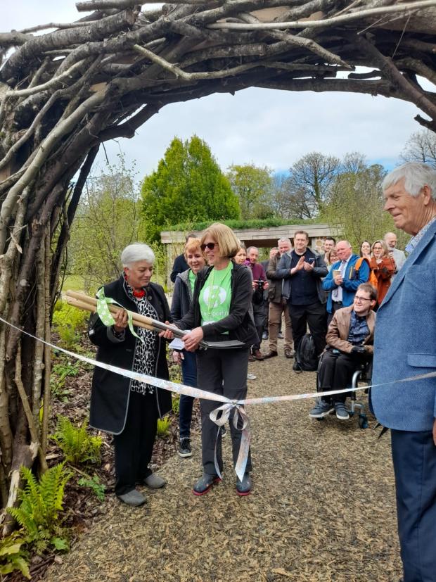Penarth Times: Sue Allen of Greenfingers Charity presenting spades to volunteers at the opening of Ty Hafan's sensory garden
