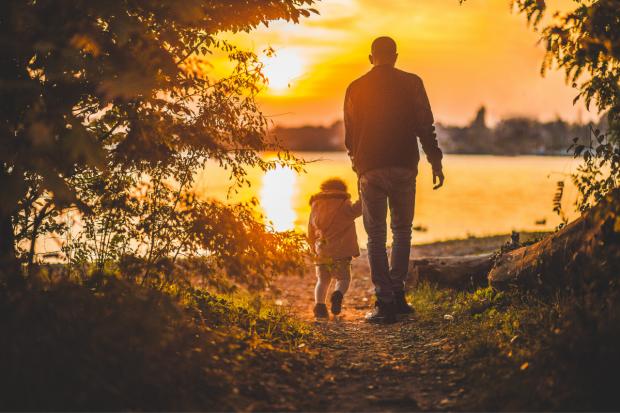Penarth Times: Father and child walking together at sunset. Credit: Canva