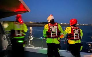 An upturned kayak, two people swimming in the water and a major emergency search